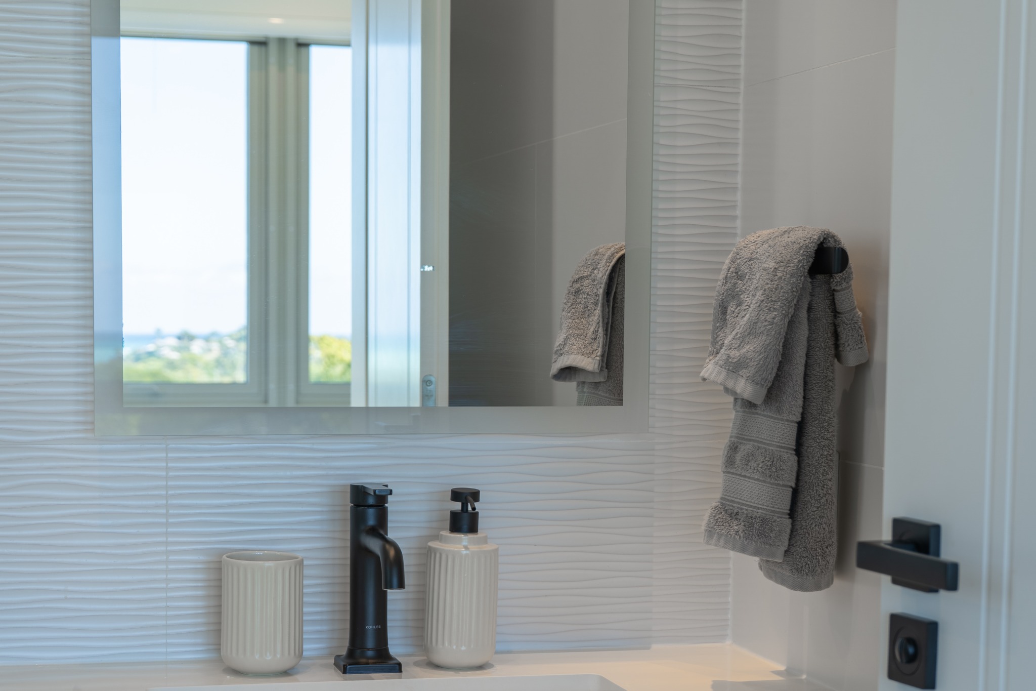 Luxury ensuite bathroom with rain shower head and ocean view window