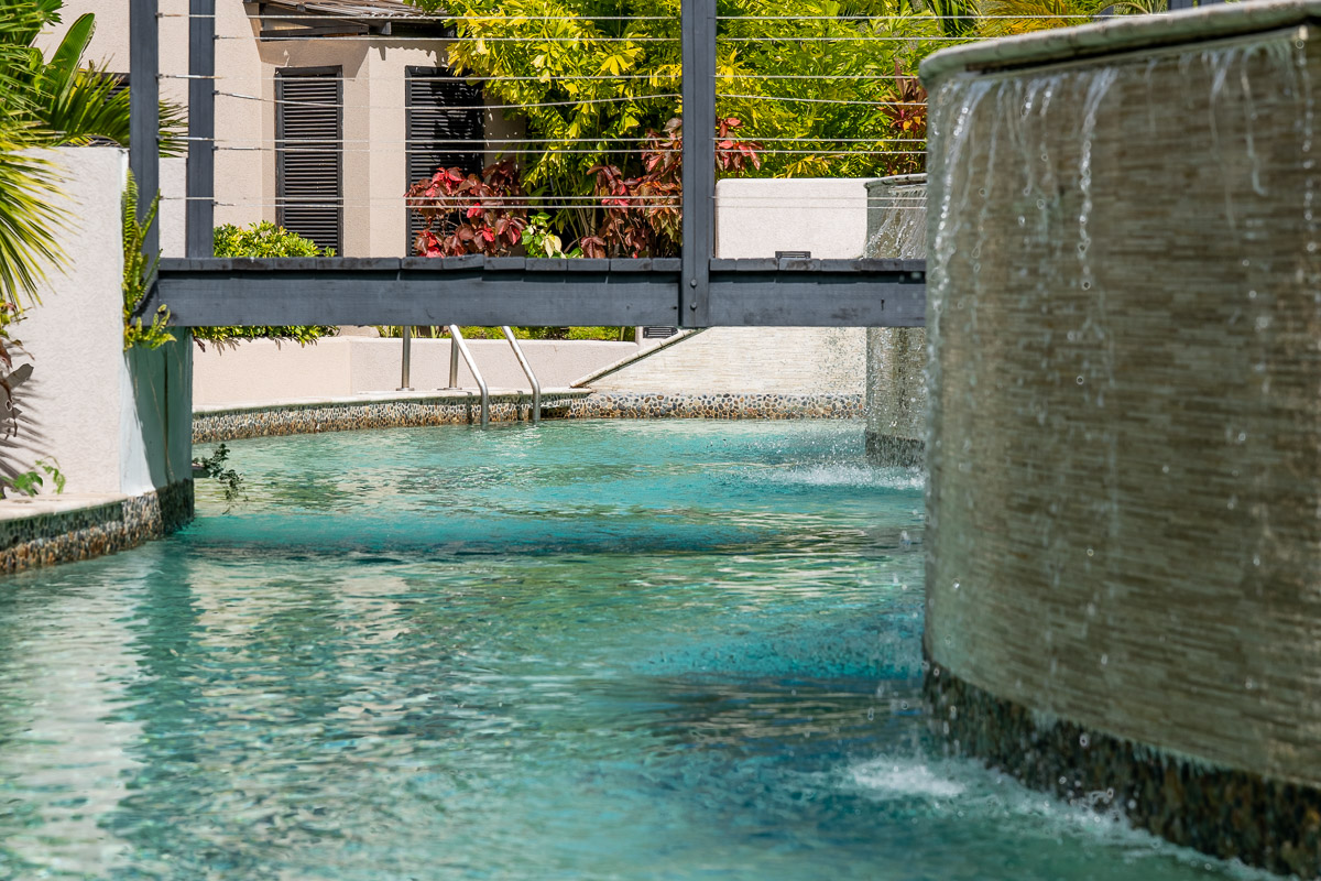 Sugar Ridge resort pool and waterfall feature surrounded by tropical hillside landscaping